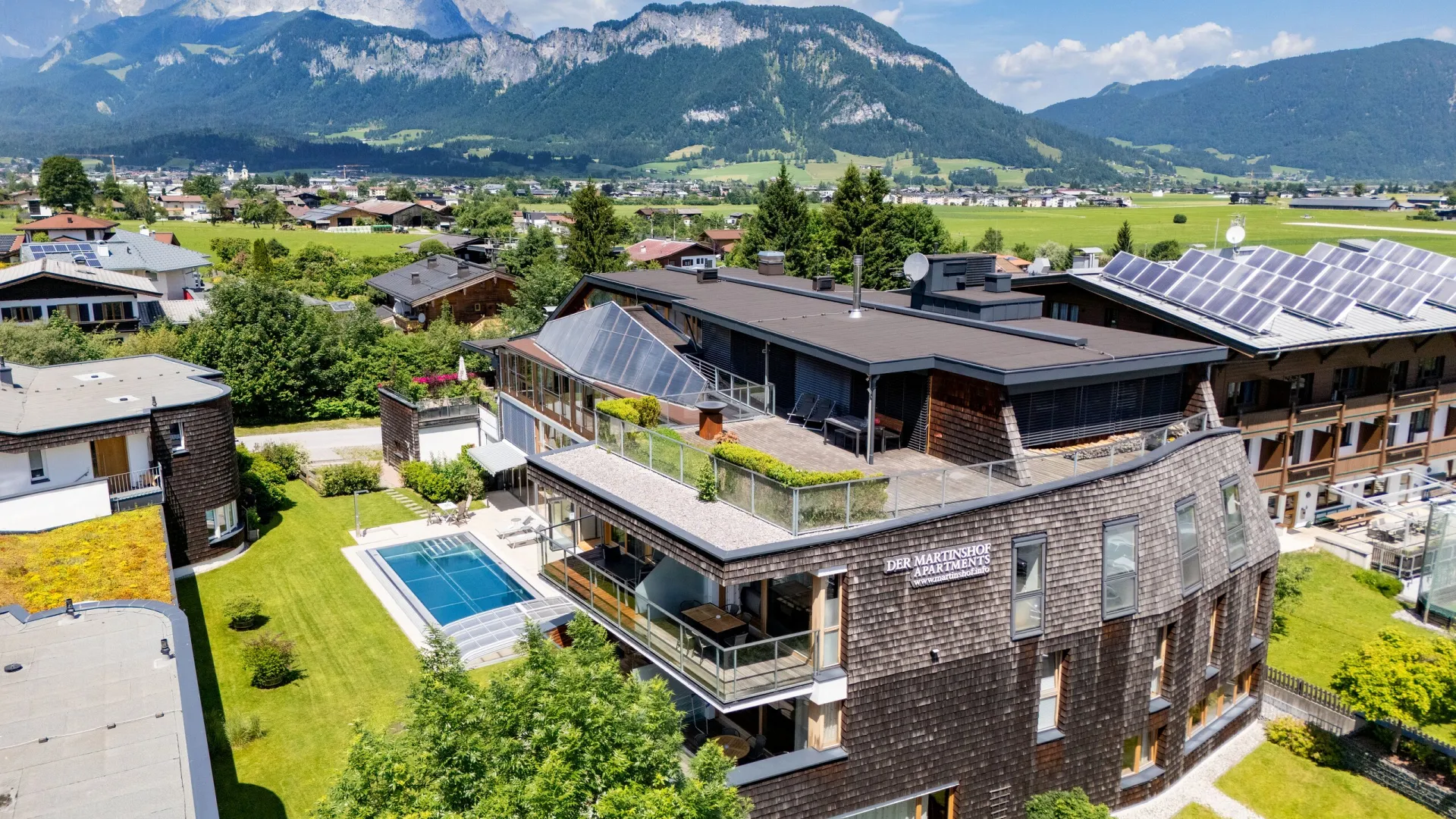 Apartmenthaus Martinshof mit Garten und Pool, dahinter der Wilde Kaiser