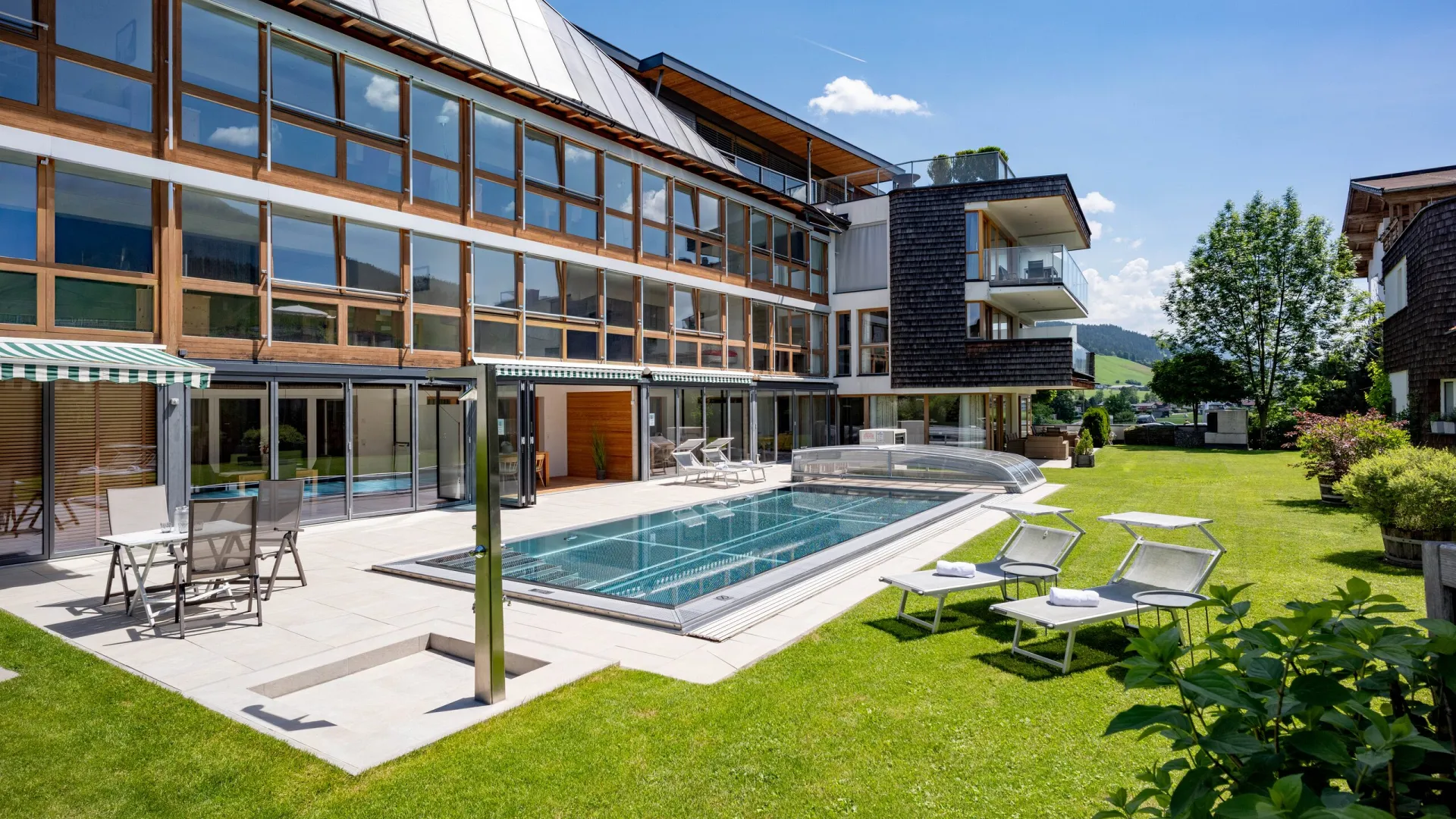 Garten mit Außenpool und Sonnenliegen vor dem Apartmenthaus