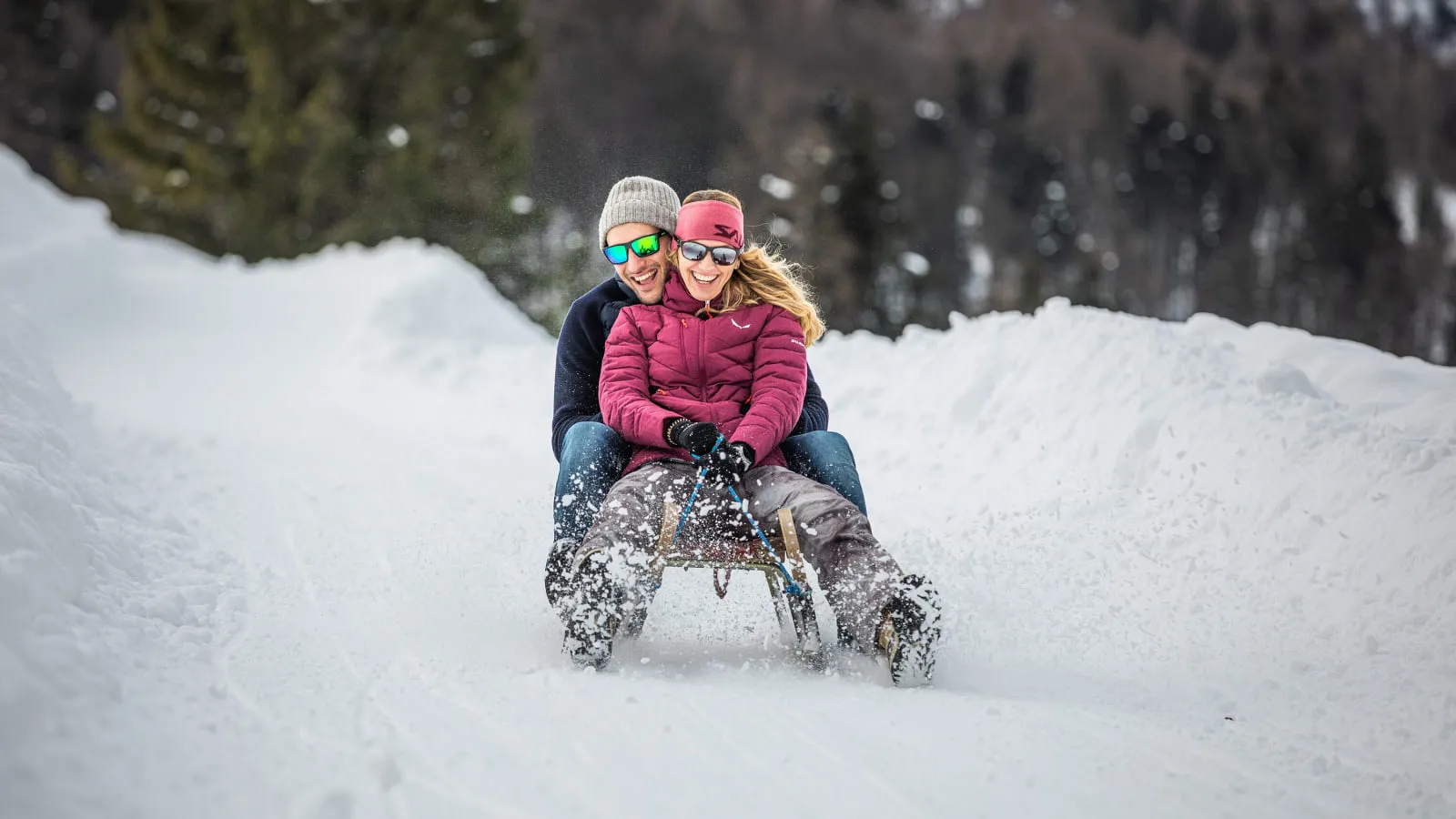 Paar fährt mit dem Rodel durch den Schnee